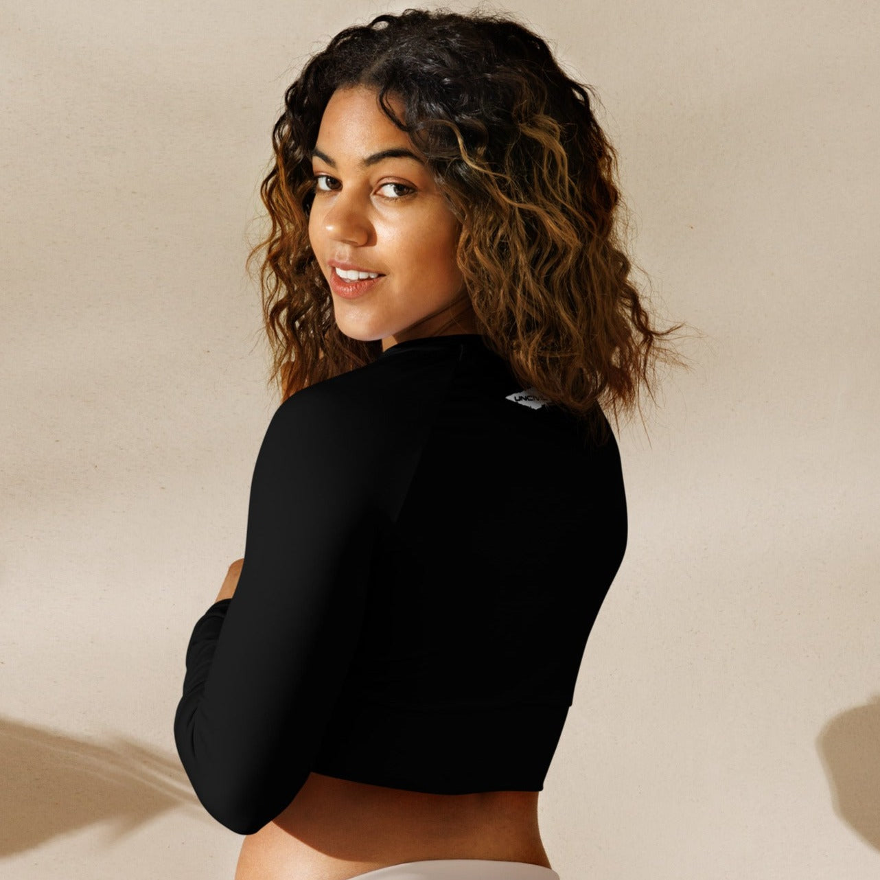 Black long-sleeve crop top for women is made of recycled polyester and elastane, making it an eco-friendly choice for swimming, sports, or athleisure. UPF 50+.