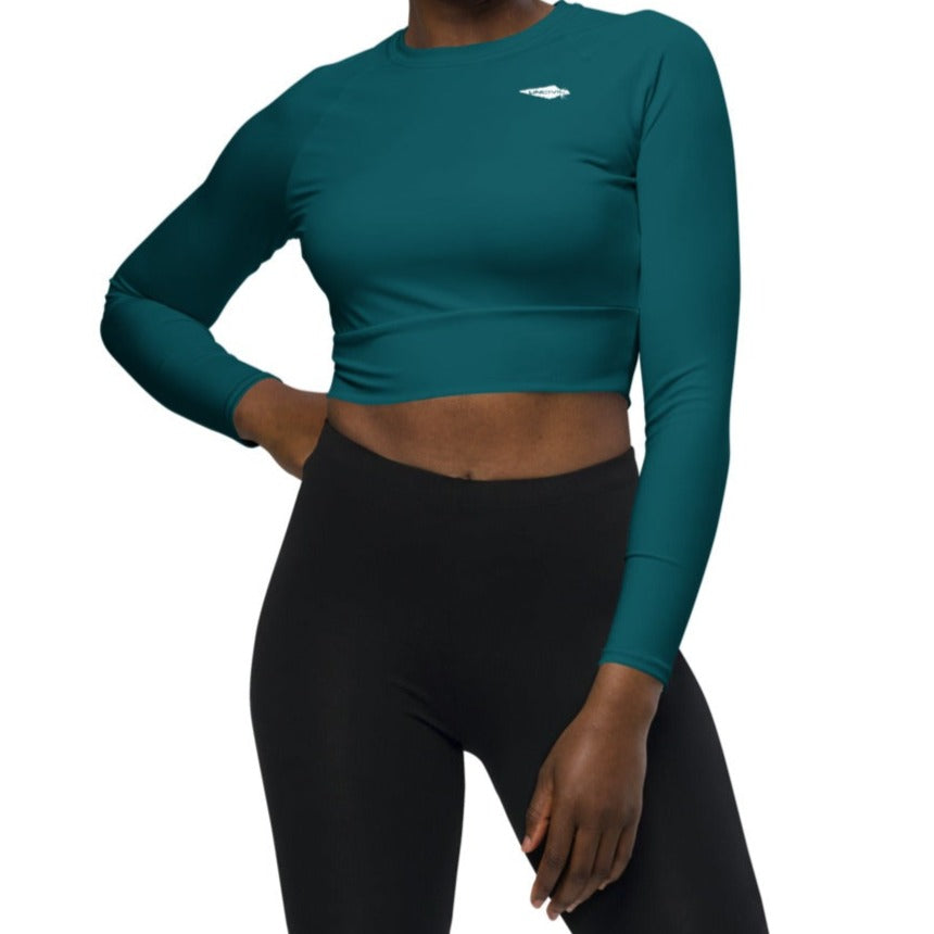 Teal long-sleeve crop top for women is made of recycled polyester and elastane, making it an eco-friendly choice for swimming, sports, or athleisure. UPF 50+.